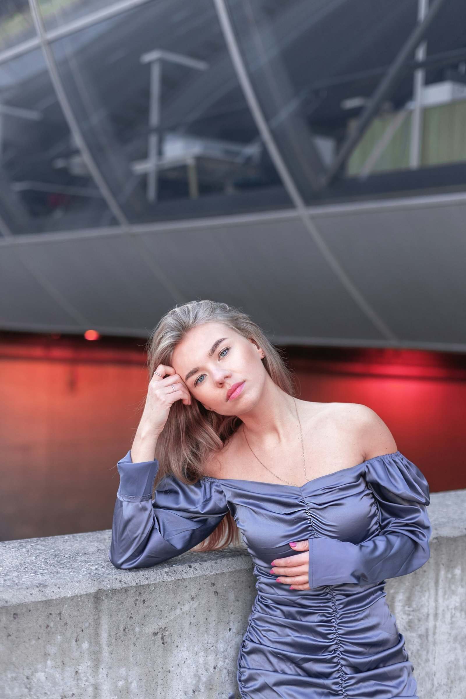 a woman in a blue dress leaning against a wall